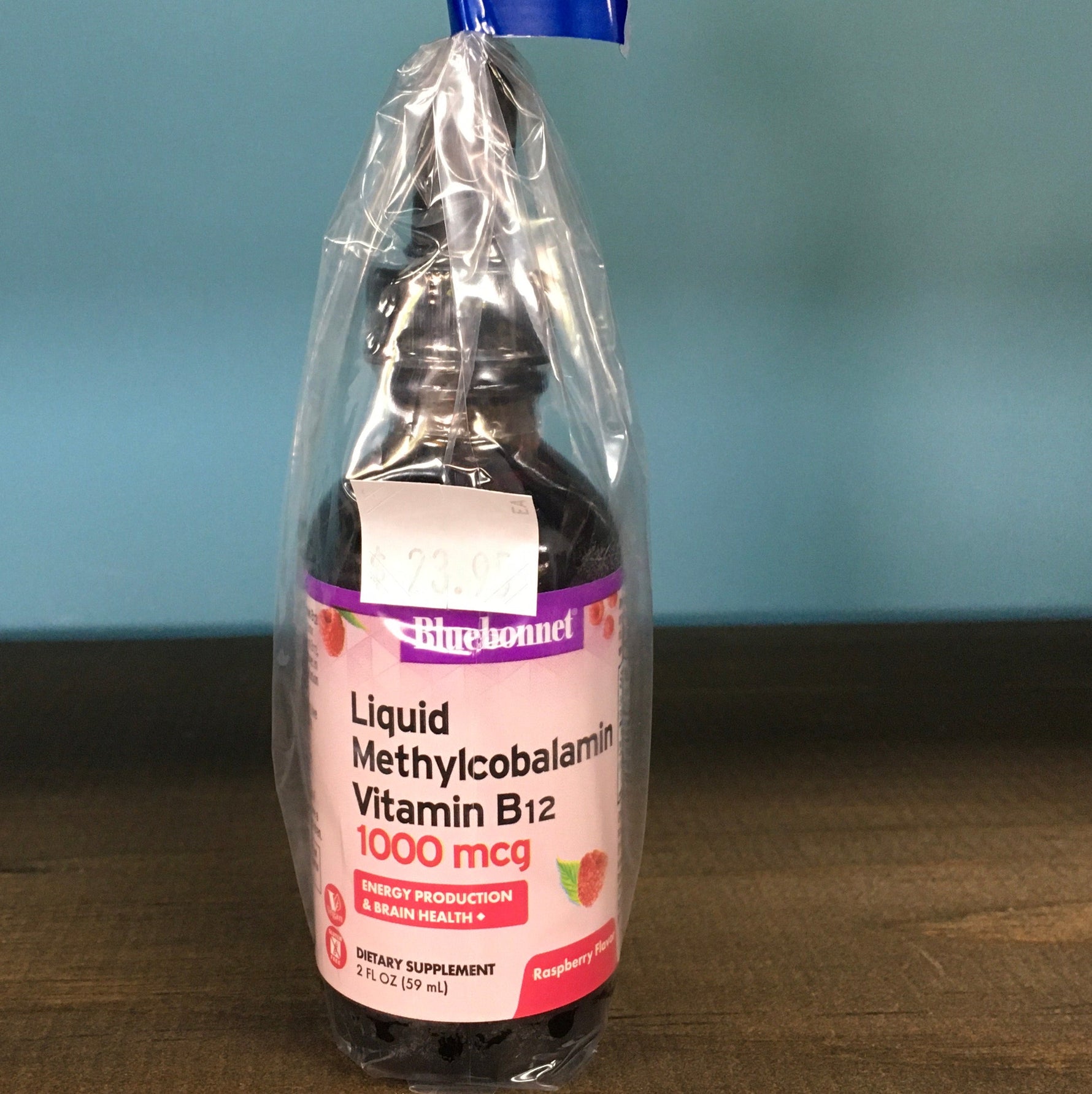 Bottle of liquid supplement with a blue cap on a wooden surface